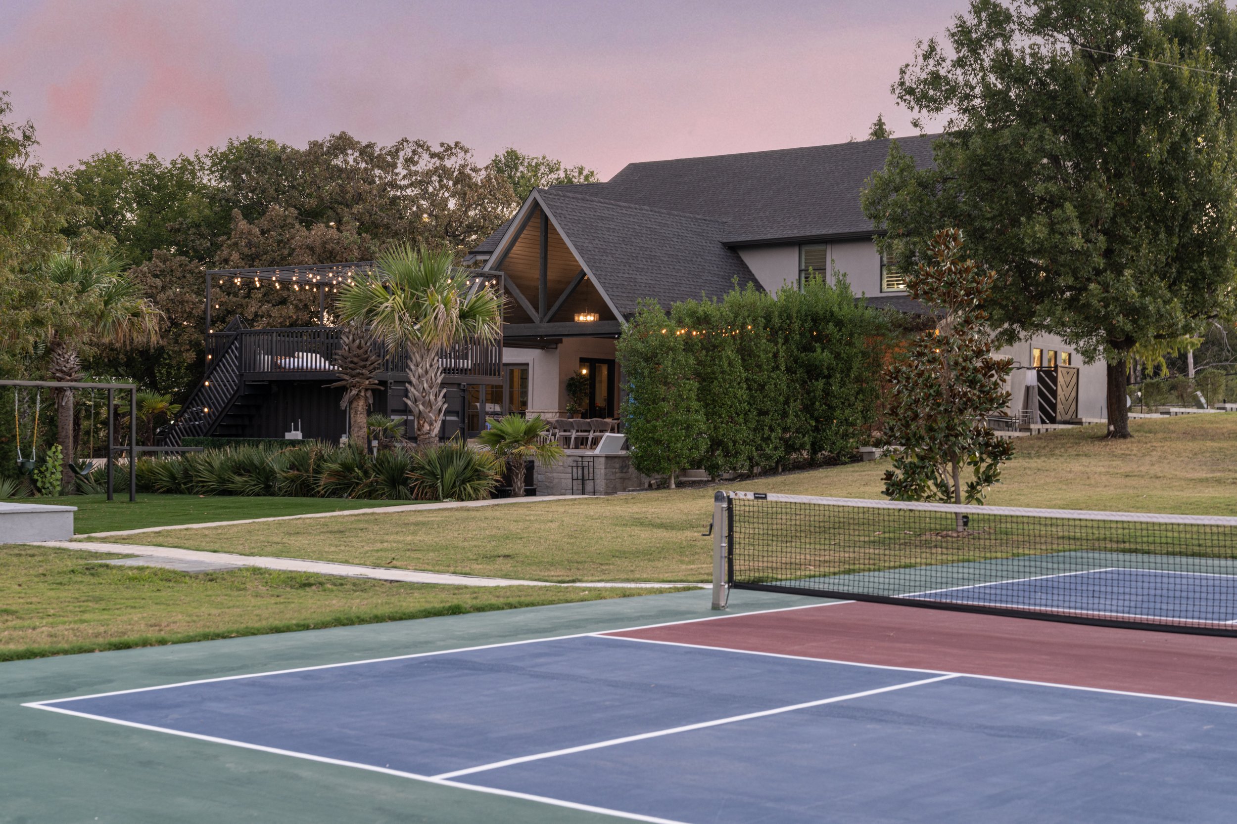 The Penrose House estate exterior with tennis court and pool at dusk